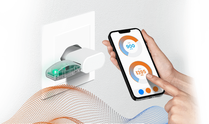 Un sensor ambiental conectado a un enchufe de pared con alguien controlando el sensor usando un teléfono inteligente.